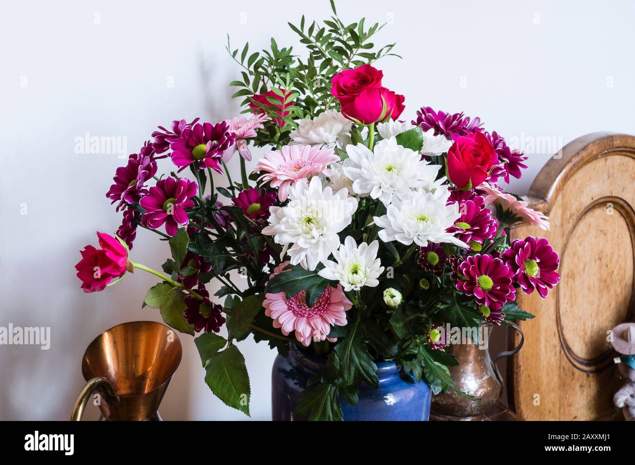 A floral arrangement indoors including red roses and  pink and white chrysanthemums in winter UK Stock Photo