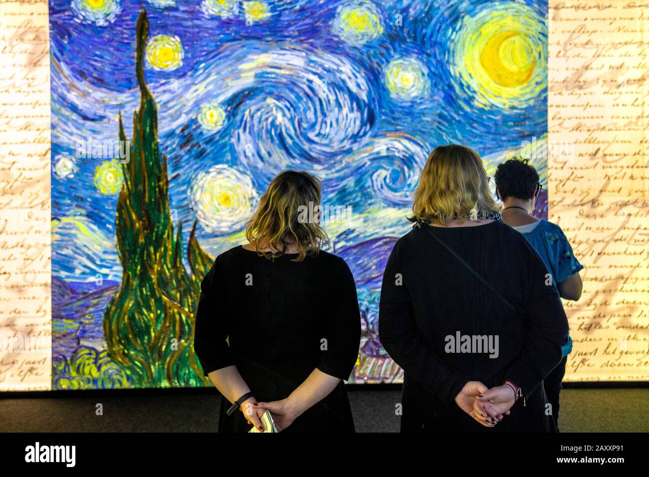 Visitors looking at Van Gogh's 'Starry Night' displayed on a digital wall at Meet Vincent van Gogh Experience 2020, London, UK Stock Photo