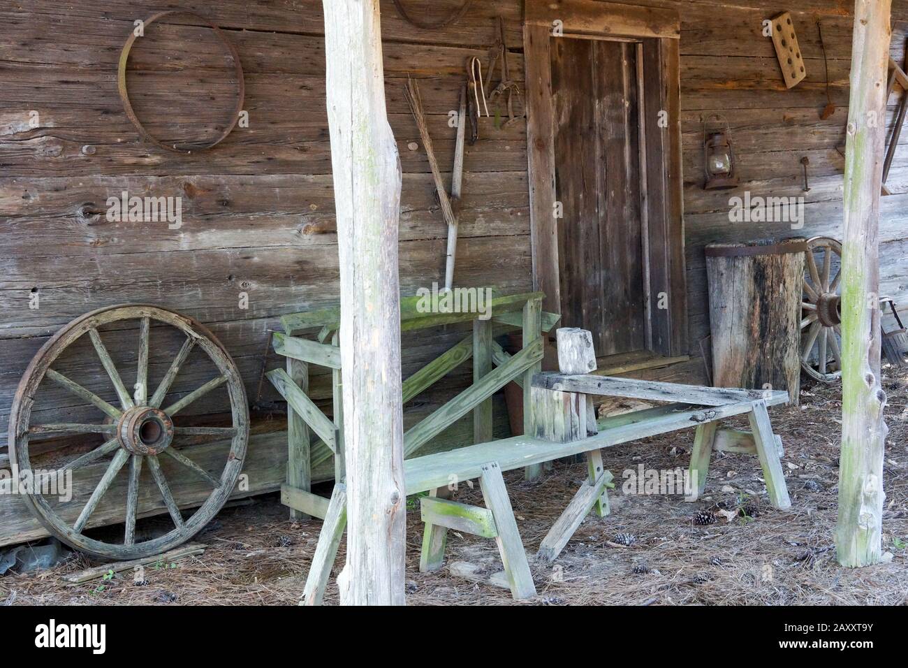 Wooden bench and wheel on the front porch of an old log house in Washington, Georgia. This log house was built in the pioneer days of America. Stock Photo