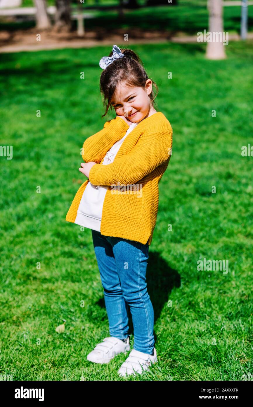 Little girl outdoors with yellow jacket standing at the park Stock