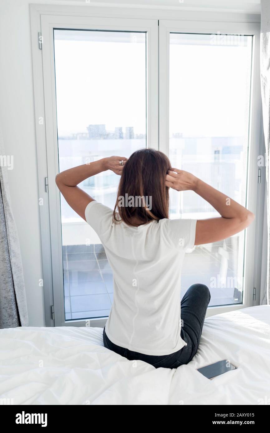 Adult woman outstretching her arms sitting on the bed after good night ...