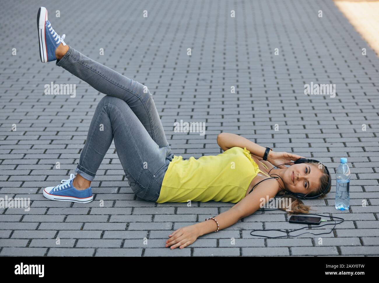 girl lying on the sidewalk in the summer and quietly listening to music Stock Photo Alamy