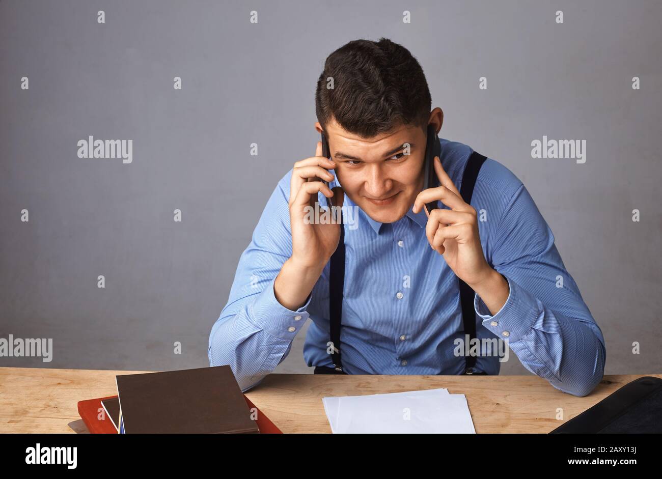 man with two phones near his ears. He actively decides something Stock Photo