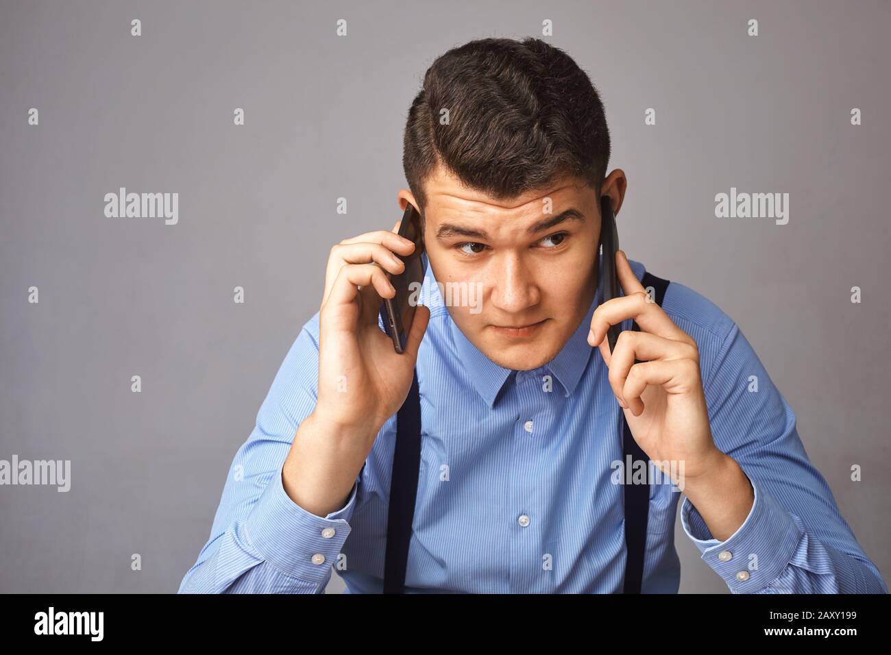 man with two phones near his ears. He actively decides something Stock Photo