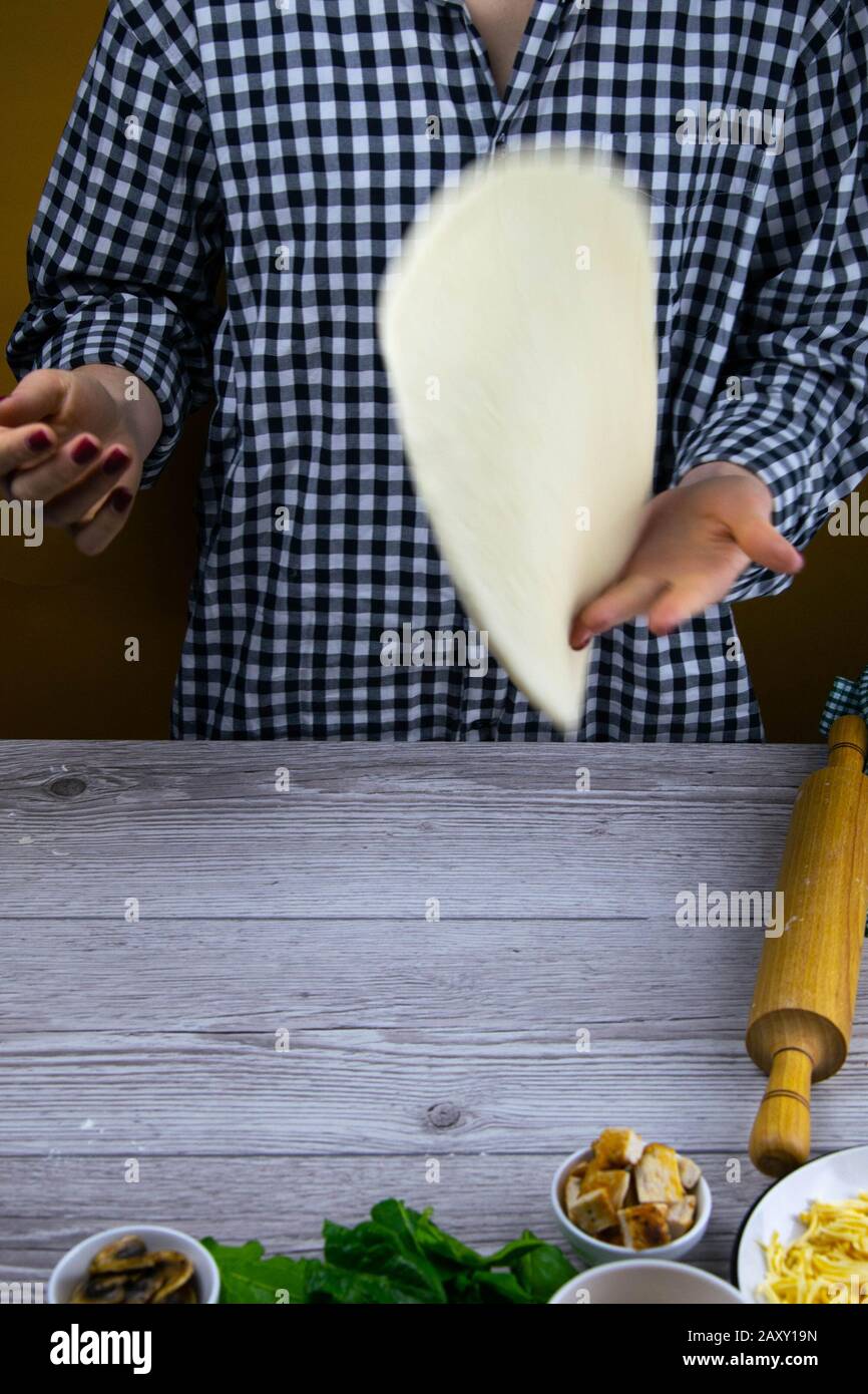 Woman tossing a slice of pizza dough. Fresh original italian raw pizza