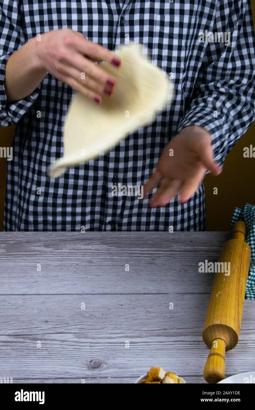 Woman tossing a slice of pizza dough. Fresh original italian raw pizza