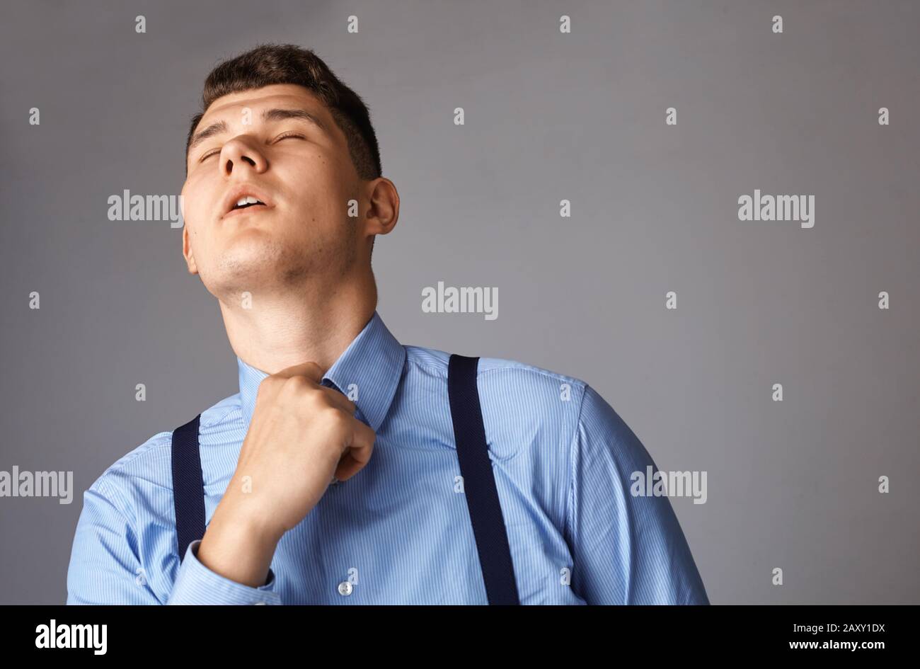 young businessman tired and trying to unbutton his shirt Stock Photo