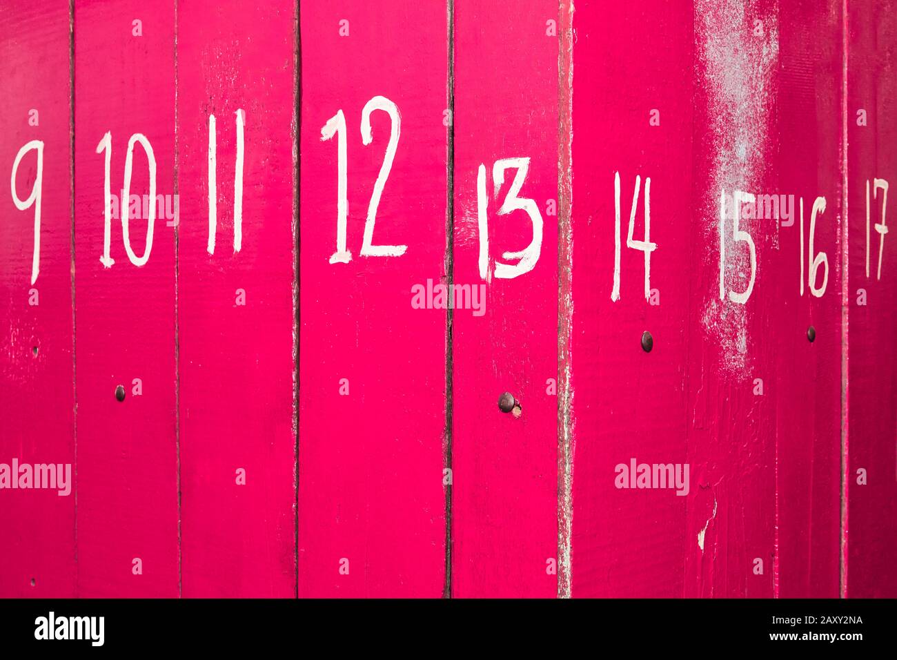 The entrance of a shop is closed with pink painted wooden panels, which are marked with big white numbers. It is often seen in the Philippines, Asia. Stock Photo