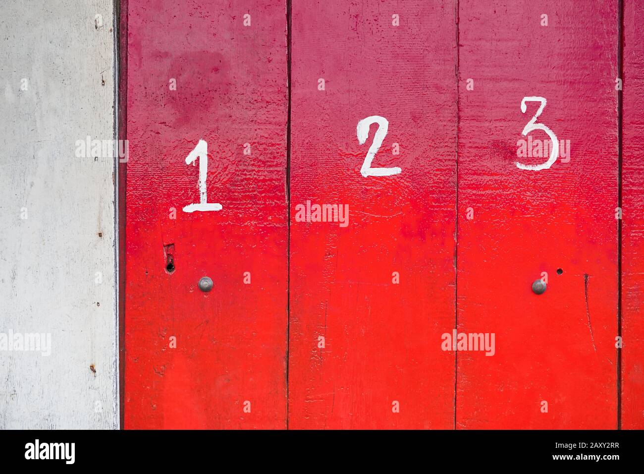 The entrance of a shop is closed with red painted wooden panels, which are marked with white numbers. It is often seen in the Philippines, Asia. Stock Photo