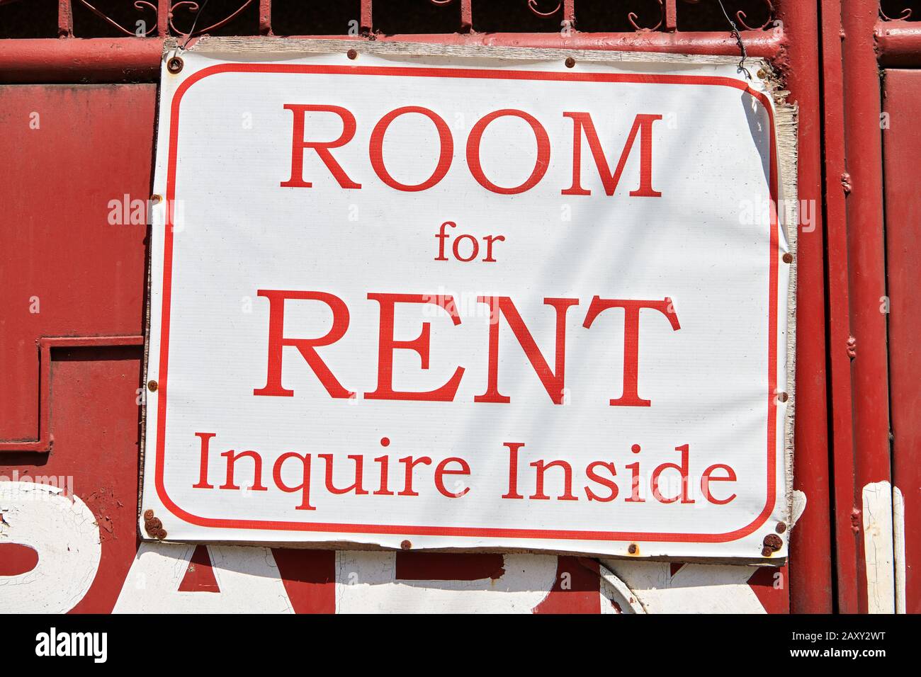 Sign with offered room for rent hanging outside of a red painted old metal gate. Inquire inside is written on the white tarpaulin, Philippines, Asia Stock Photo