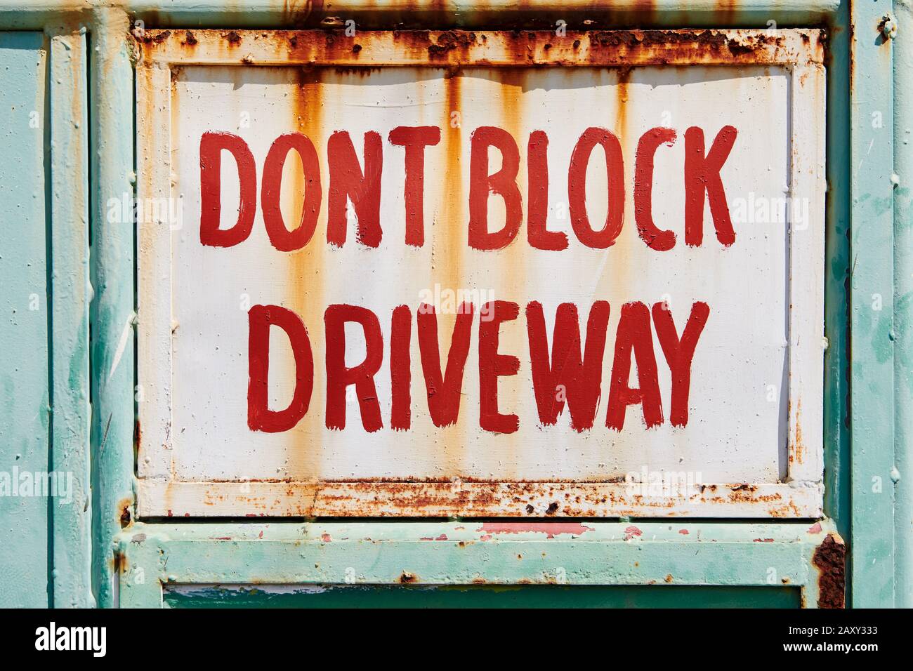 Close-up of a rusty painted sign 'Don't block the driveway', written in red letters on a metal gate, seen in Iloilo, Philippines, Asia Stock Photo