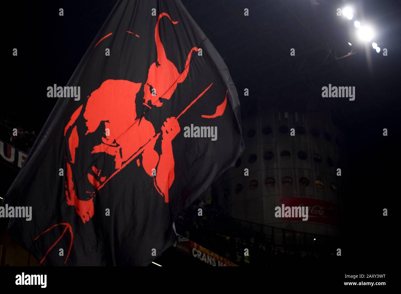 Milan, Italy - 13 February, 2020: A fan of AC Milan waves a flag with a  devil on it prior to the Coppa Italia semi final football match between AC  Milan and
