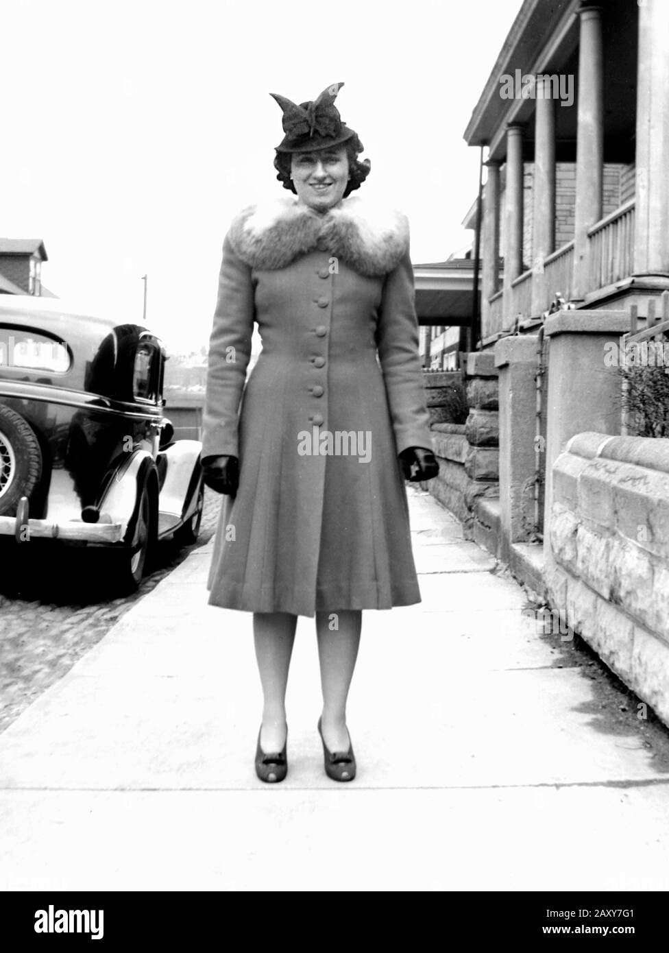 Woman with a funny hat poses on the sidewalk, ca. 1935. Stock Photo