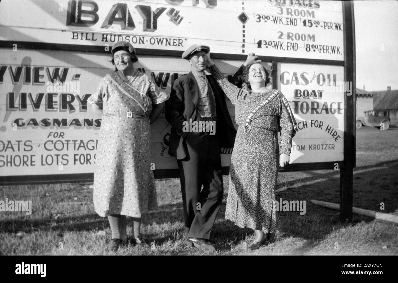 Husband and wife with mother-in-law stand in front of vacation resort sign, ca. 1925. Stock Photo