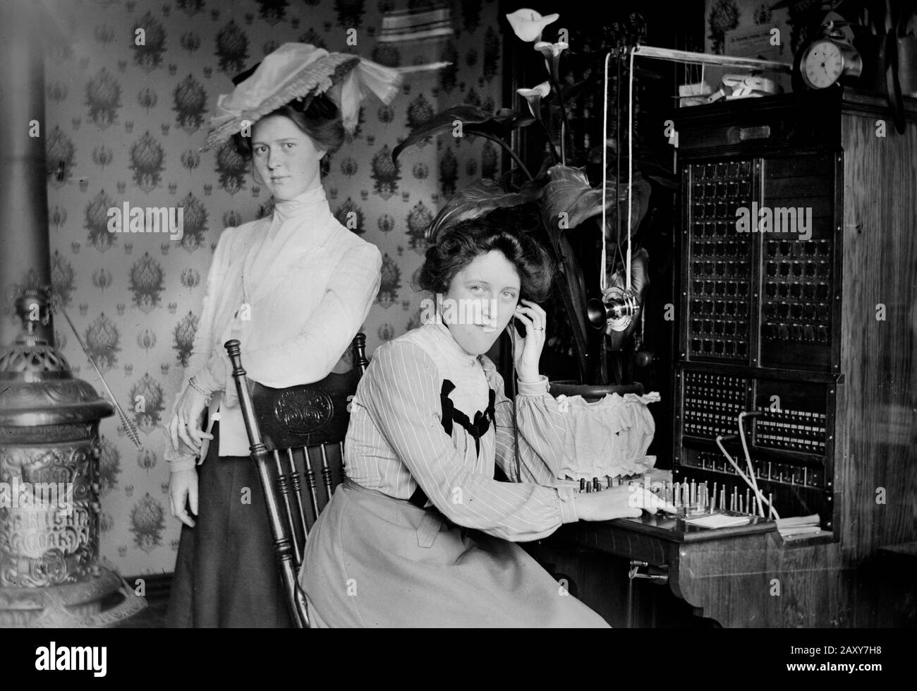 Two women pose with an early switchboard in the US, ca. 1900. Stock Photo