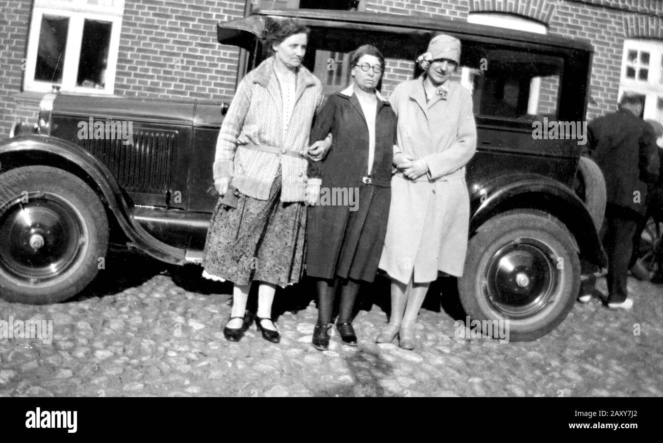 Three women pose next to their car, ca. 1928. Stock Photo