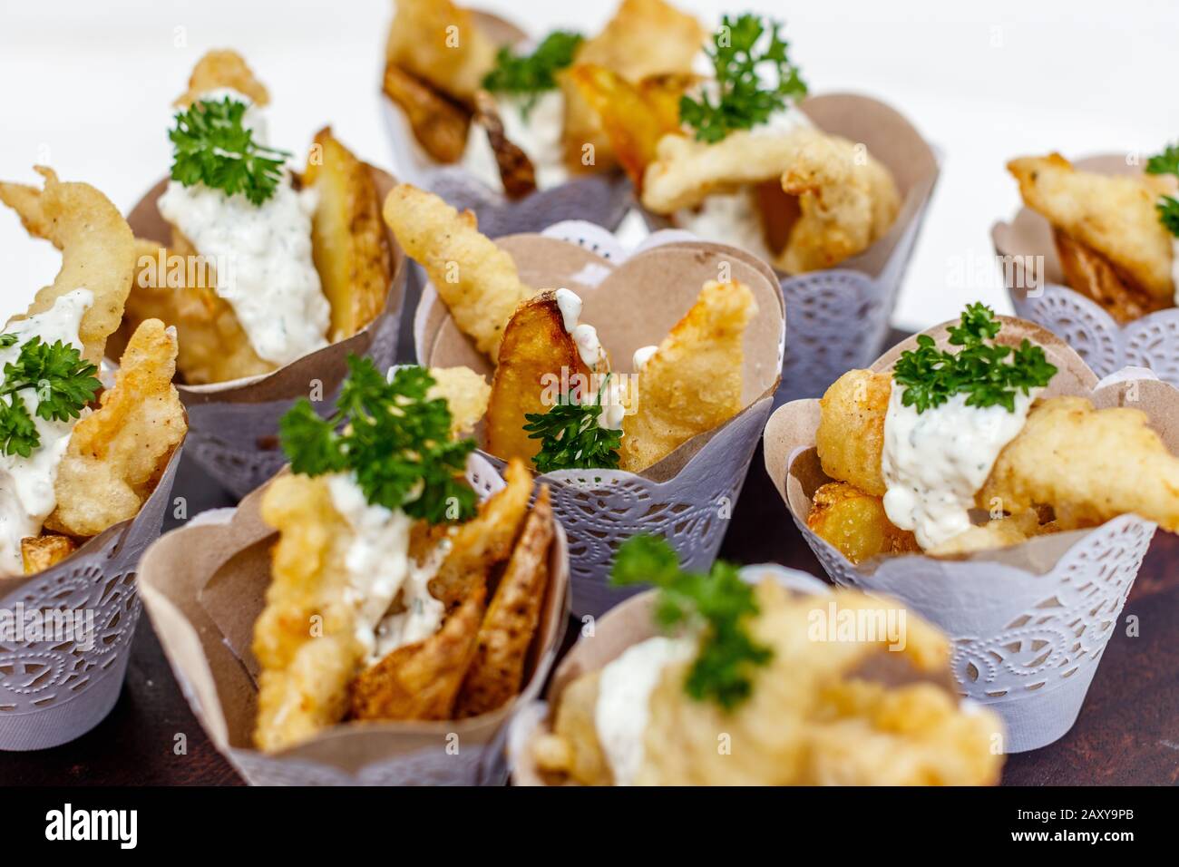Fish and chips served in paper cones for individual serving. Decorated with parsley. Stock Photo
