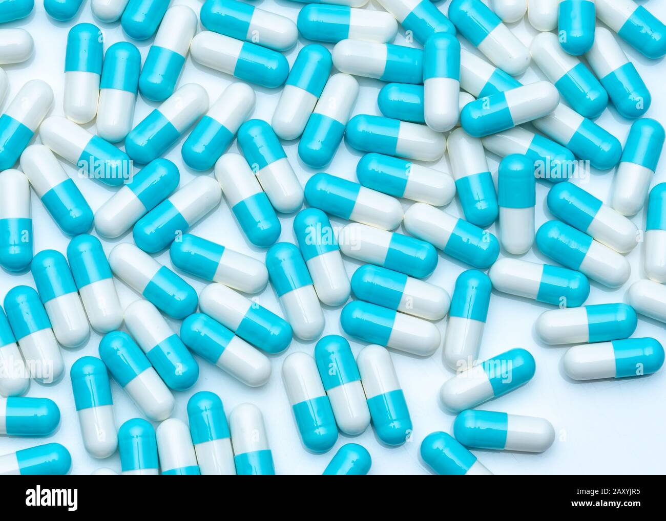 Blue-white capsule pills on white table. Full frame of capsule drug pills. Pharmacy product. Pharmaceutical production concept. Pharmaceutics. Stock Photo
