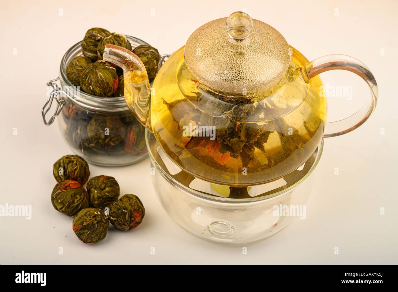 Flower tea brewed in a glass teapot, flower tea balls and a jar of tea on a white background. Close up Stock Photo