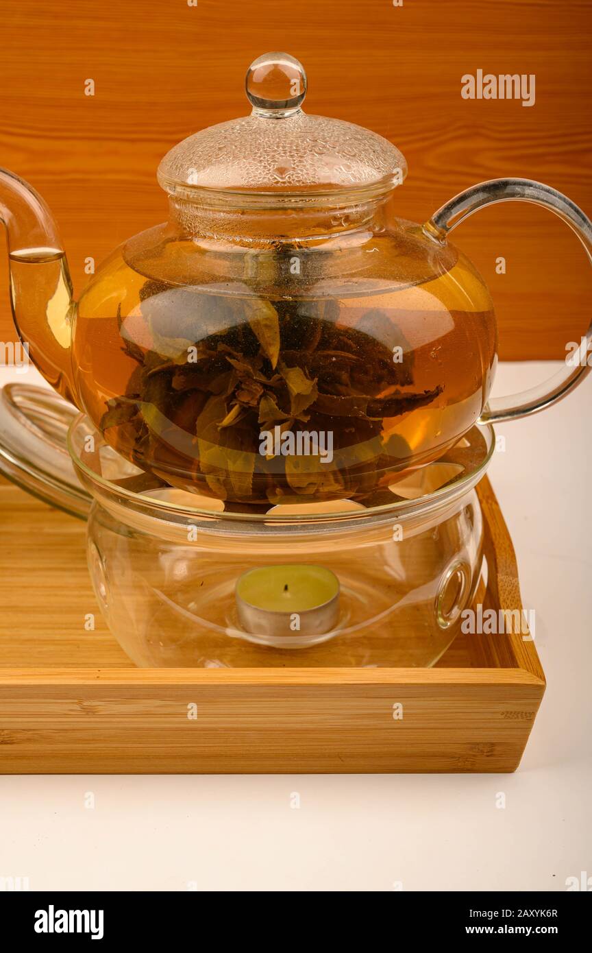 https://c8.alamy.com/comp/2AXYK6R/flower-tea-brewed-in-a-glass-teapot-on-a-wooden-tray-on-a-white-background-close-up-2AXYK6R.jpg