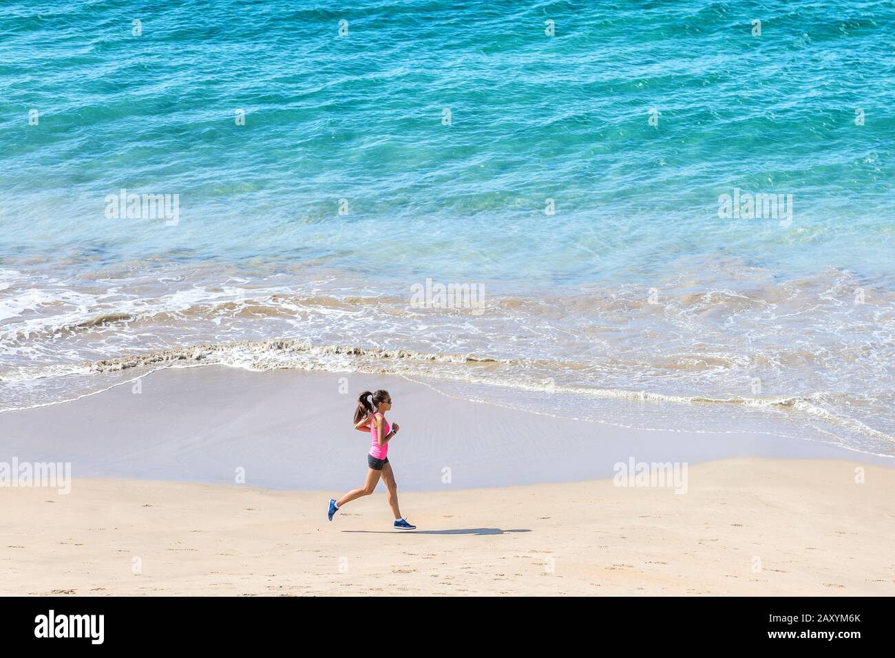 Woman runner training cardio running by the ocean on the beach. Morning ...