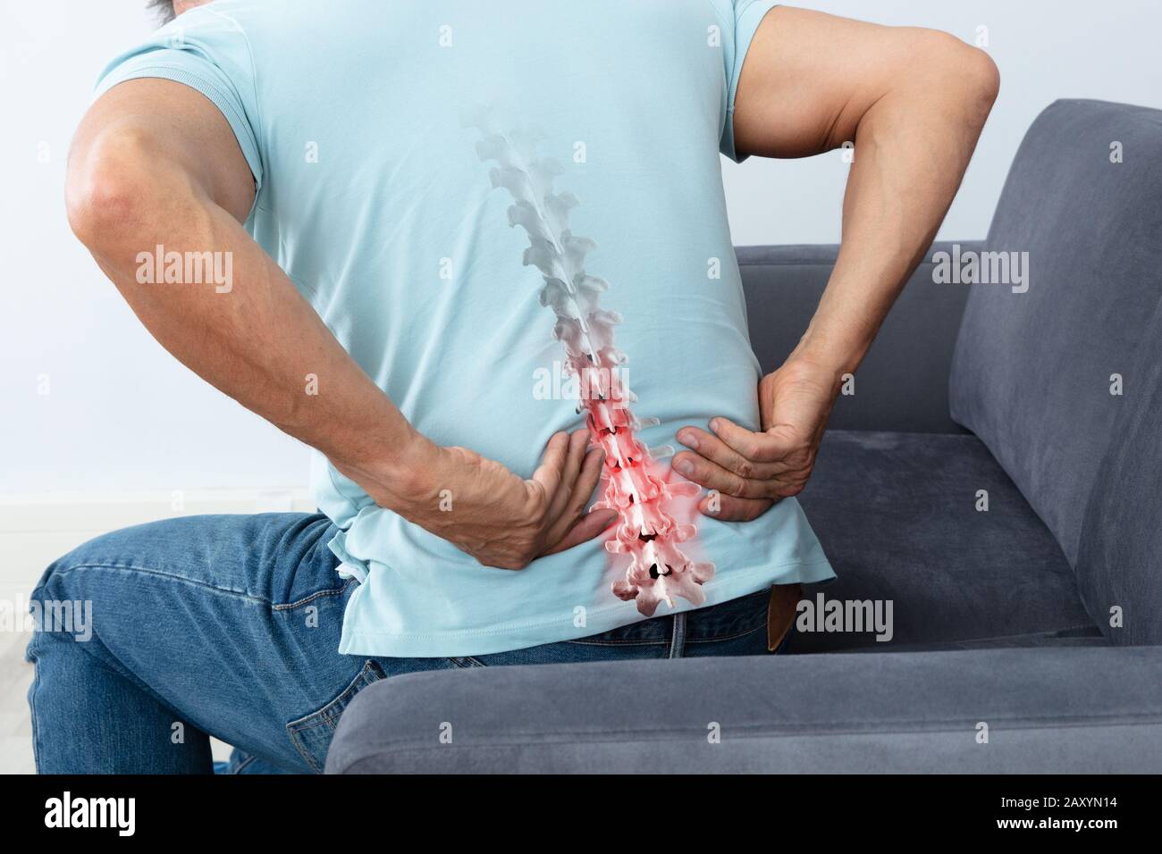 Mature Man Sitting On Sofa Suffering From Back Pain Stock Photo - Alamy