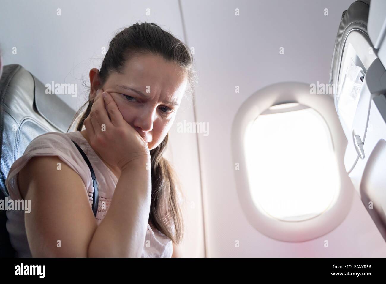 Young Woman Having Anxiety Attack In Airplane Stock Photo