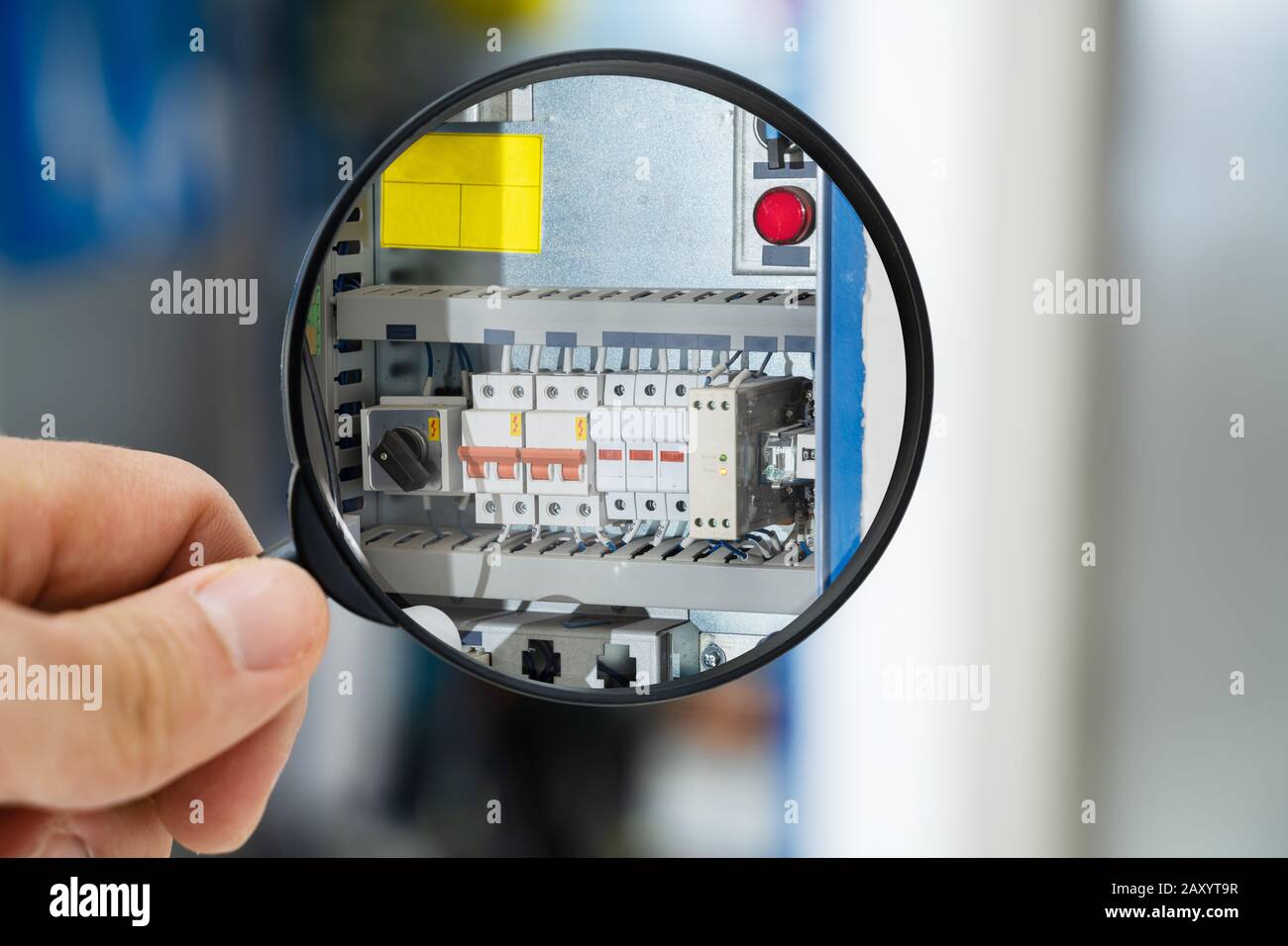 Male Technician Examining Fusebox With Magnifying Glass Stock Photo