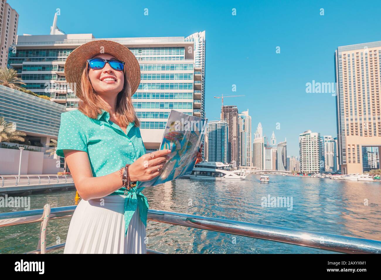 A happy traveller girl with a map on a cruise ship at the Marina port in Dubai. Travel destinations and transport concept Stock Photo