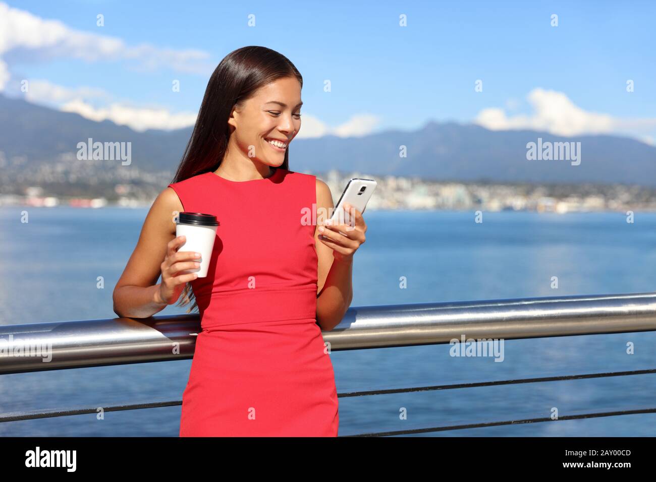 Businesswoman drinking coffee using mobile phone app to play video games online. Asian woman relaxing. Work urban city lifestyle. Stock Photo