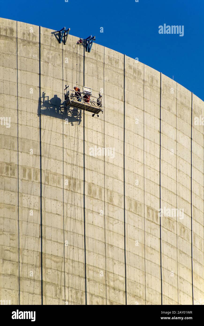 Construction worker in a lift on the outer wall of a cooling tower Stock Photo