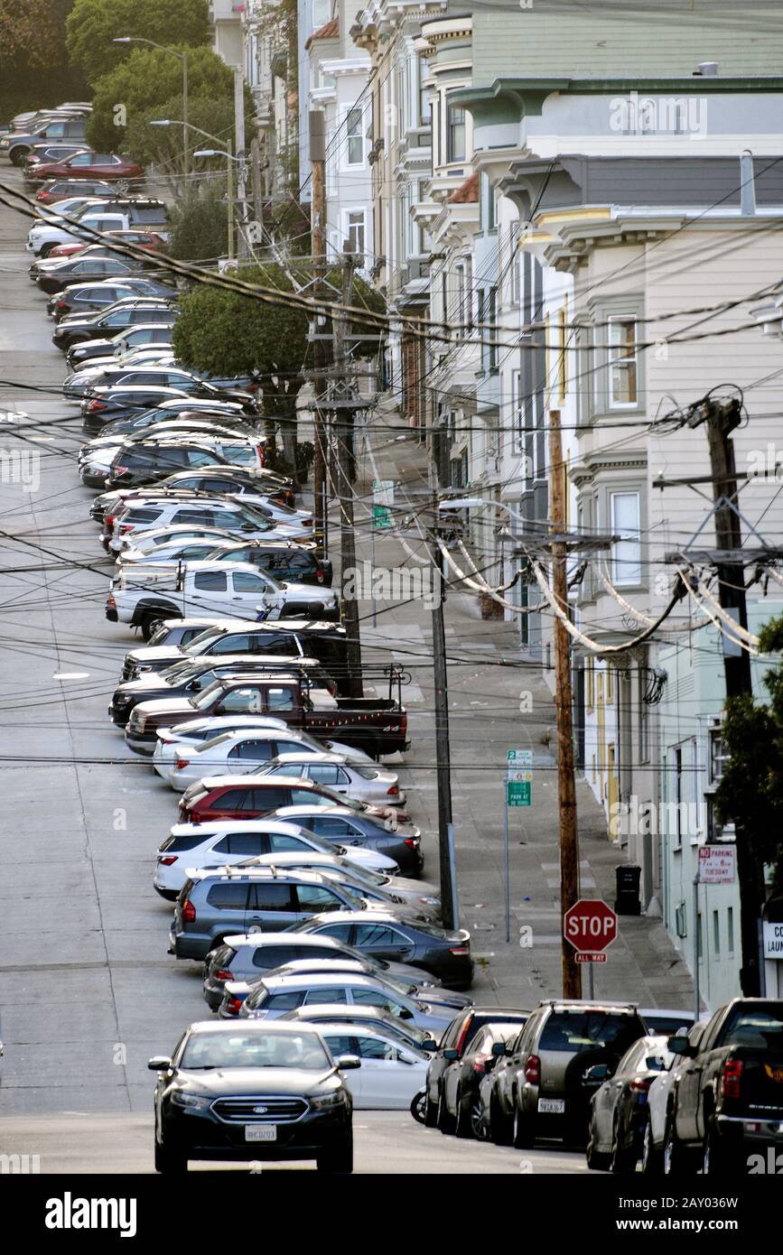 Steep road with victorian houses in North Beach with parked cars and power lines, San Francisco, California, USA Stock Photo