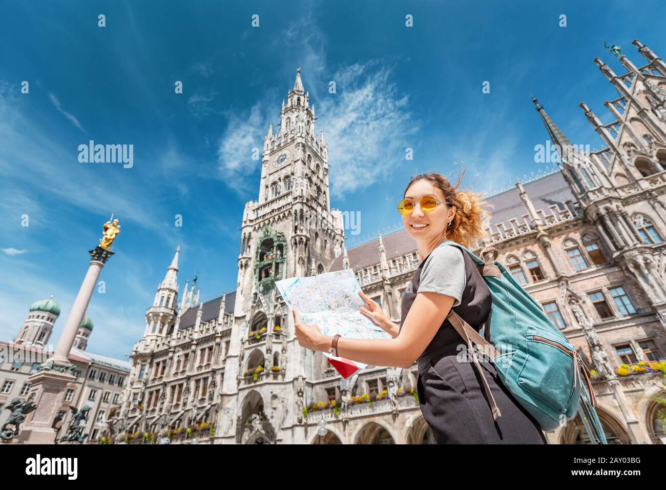 Happy asian woman with map searching for sights and interesting places in Munich city with Town Hall at the background. Stock Photo