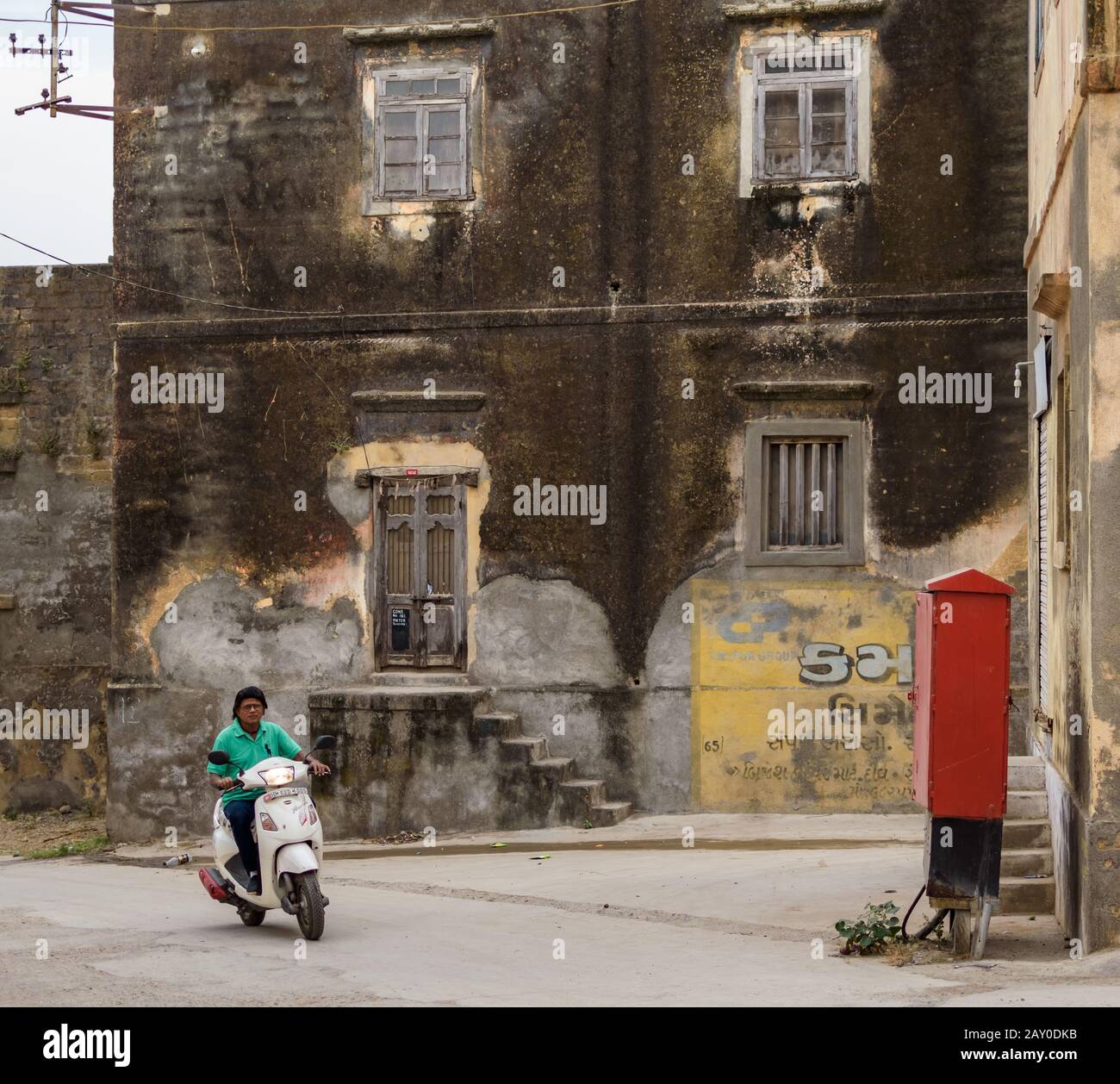Diu, India - December 2018: A man rides a scooter through the quiet streets and faded buildings in the island of Diu. Stock Photo