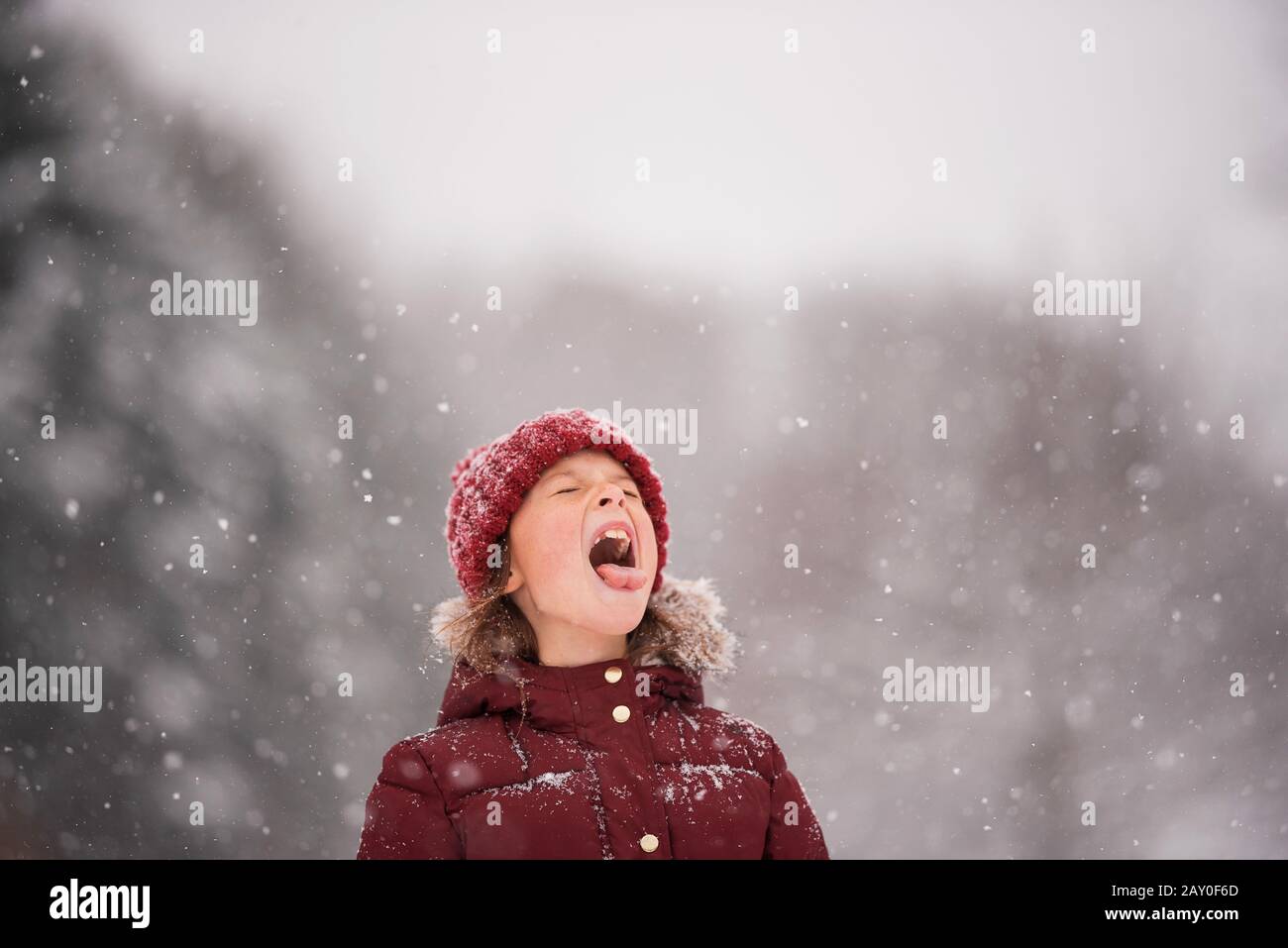 Girl standing outdoors catching snow in her mouth, Wisconsin, USA Stock Photo