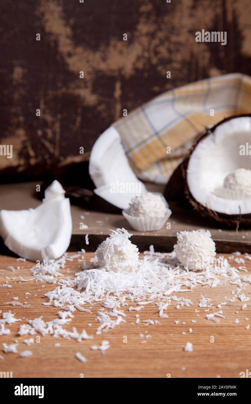 Close up of coconut with white pulp, coconut chip and sweet chocolate coconut truffles. Coconut shell, coconut flakes, small pieces of crashed nut, co Stock Photo