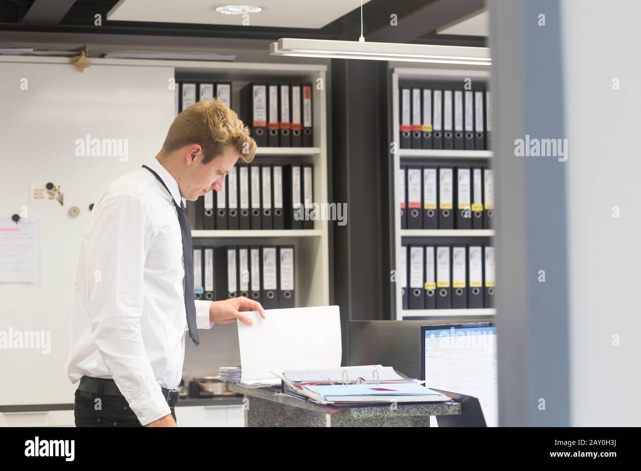 Salesman standing in a shop's office looking at a brochure, Germany Stock Photo