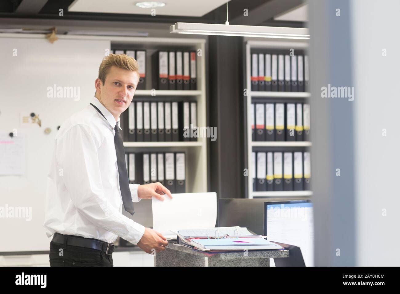 Salesman standing in a shop's office looking at a brochure, Germany Stock Photo
