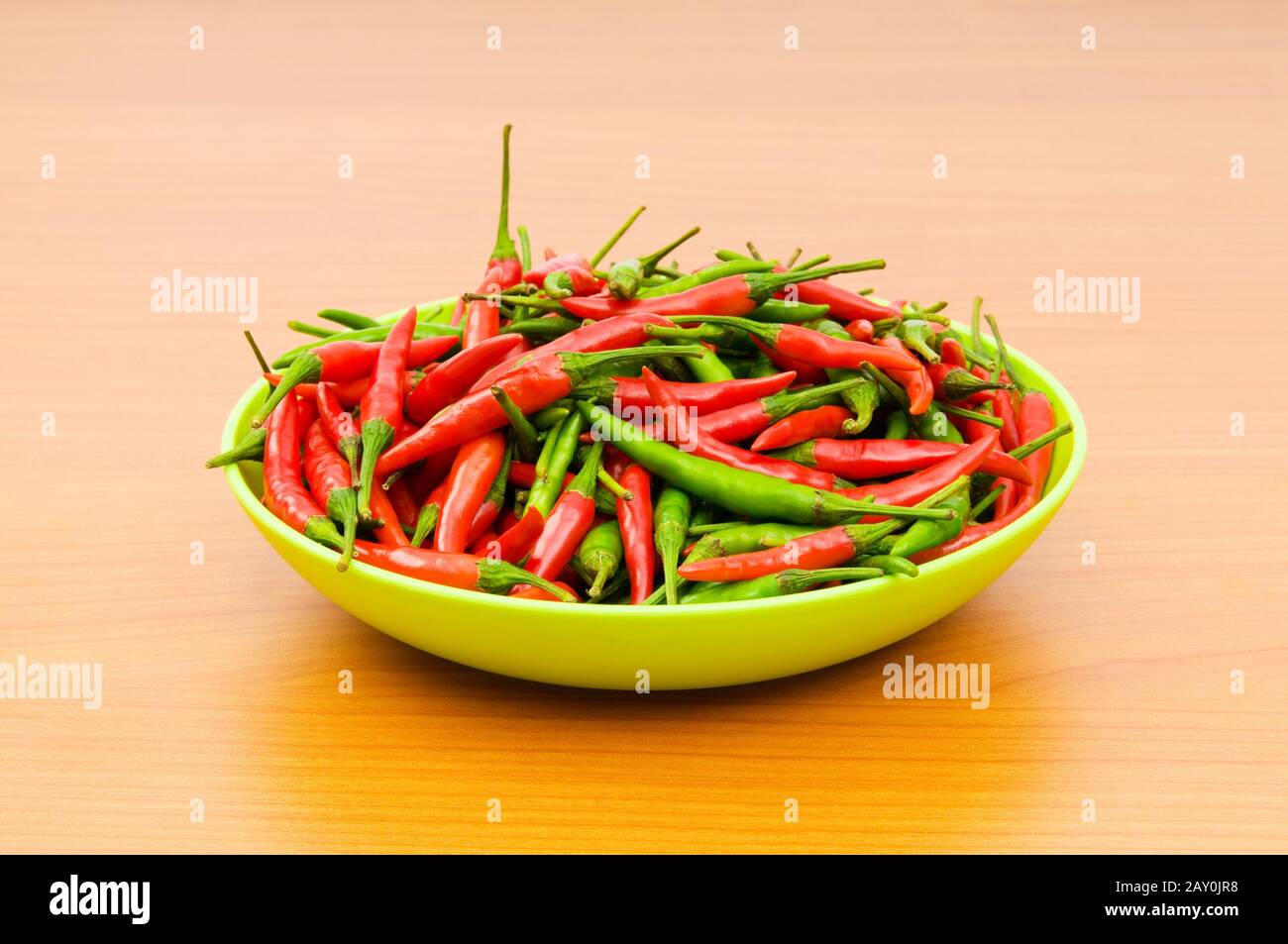 Hot peppers in the plate on wooden table Stock Photo