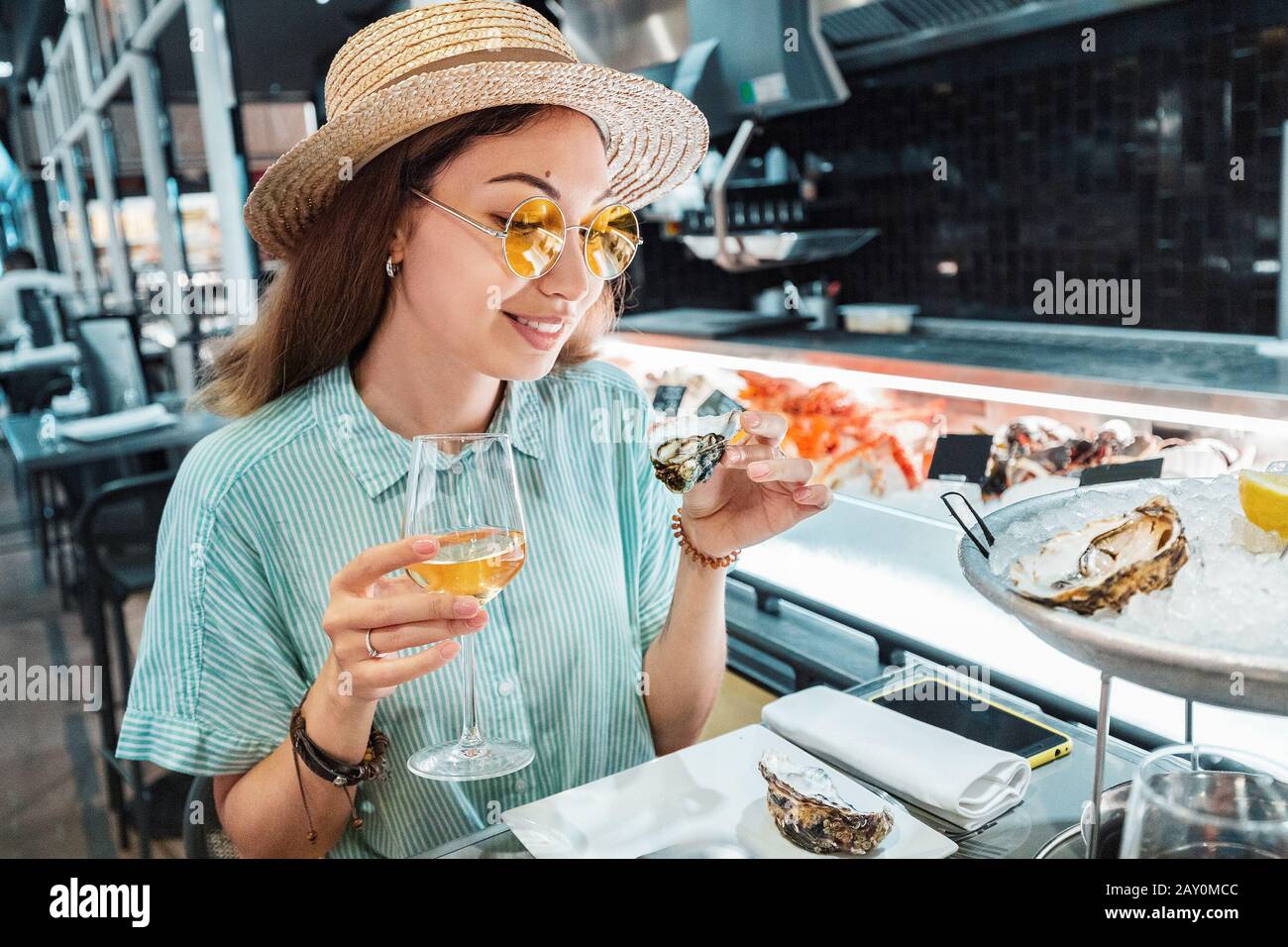 Asian woman tasting fresh raw oyster shellfish and drinking wine in seafood restaurant Stock Photo