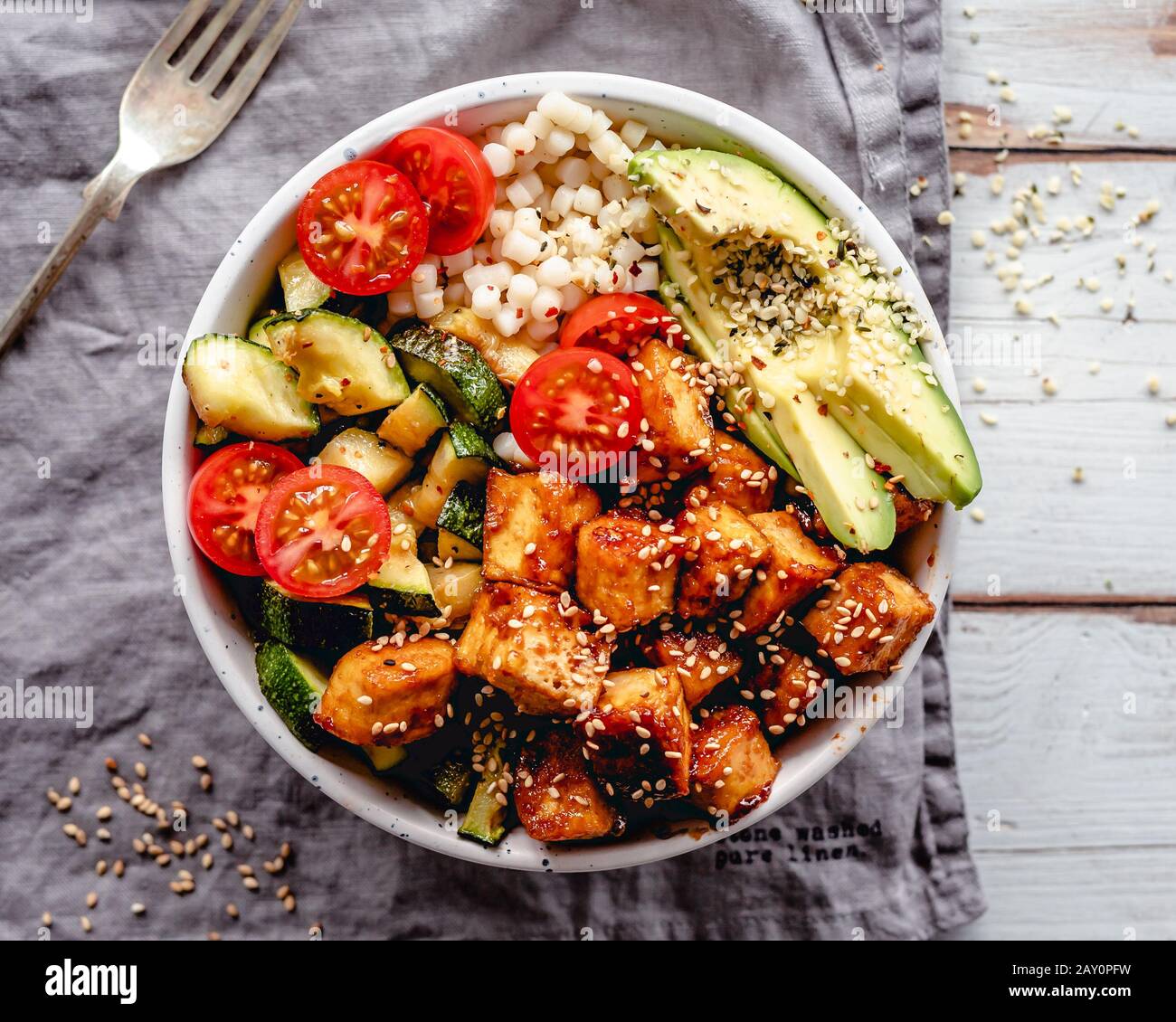 Pan fried tofu with pearl cous-cous, fried courgette, avocado, tomato and sesame seeds Stock Photo