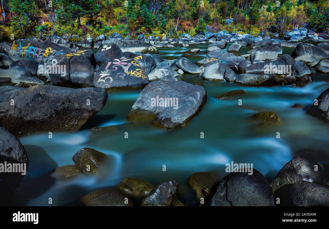 Mantras painted on the rocks dotted across the stream Stock Photo