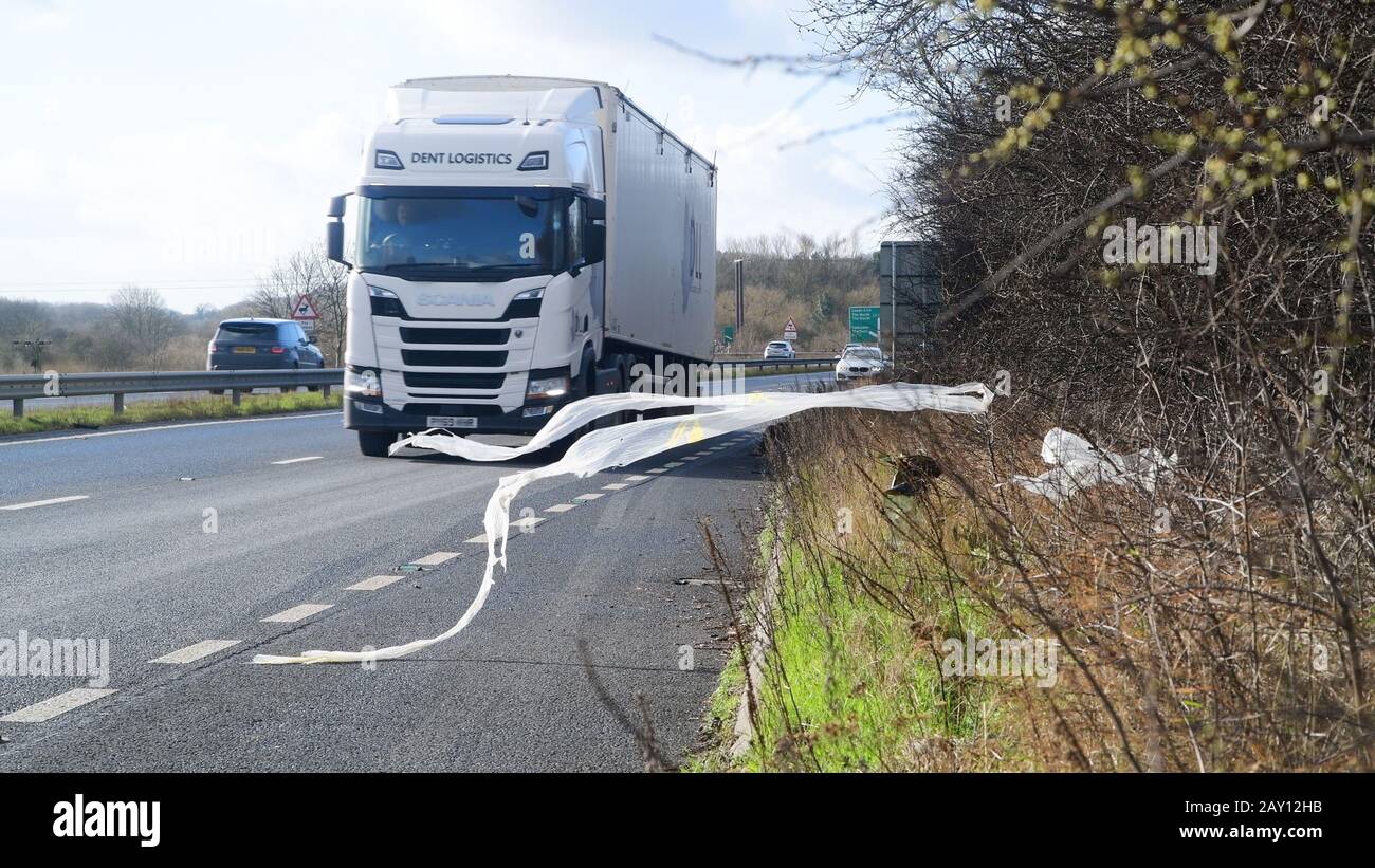 traffic passing dumped plastic rubbish in layby on A64  blowing in the wind leeds united kingdom Stock Photo