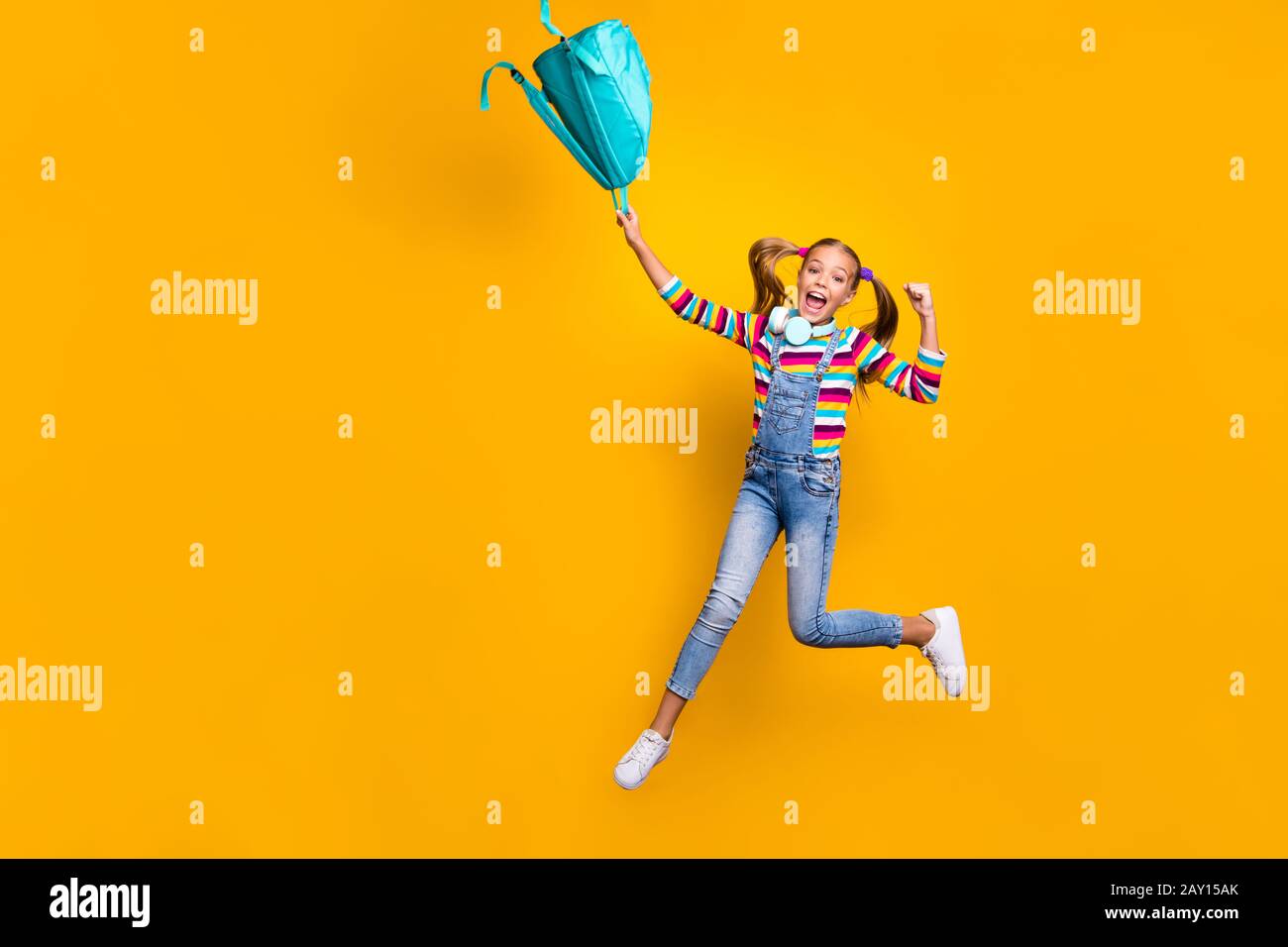 Yeah i pass exams. Ful size photo crazy energetic ecstatic schoolkid jump throw blue bag rucksack wear striped sweater denim casual style jeans Stock Photo