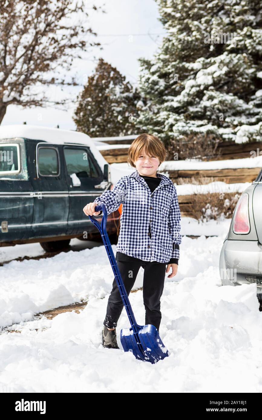 A six year old boy shoveling snow in driveway Stock Photo