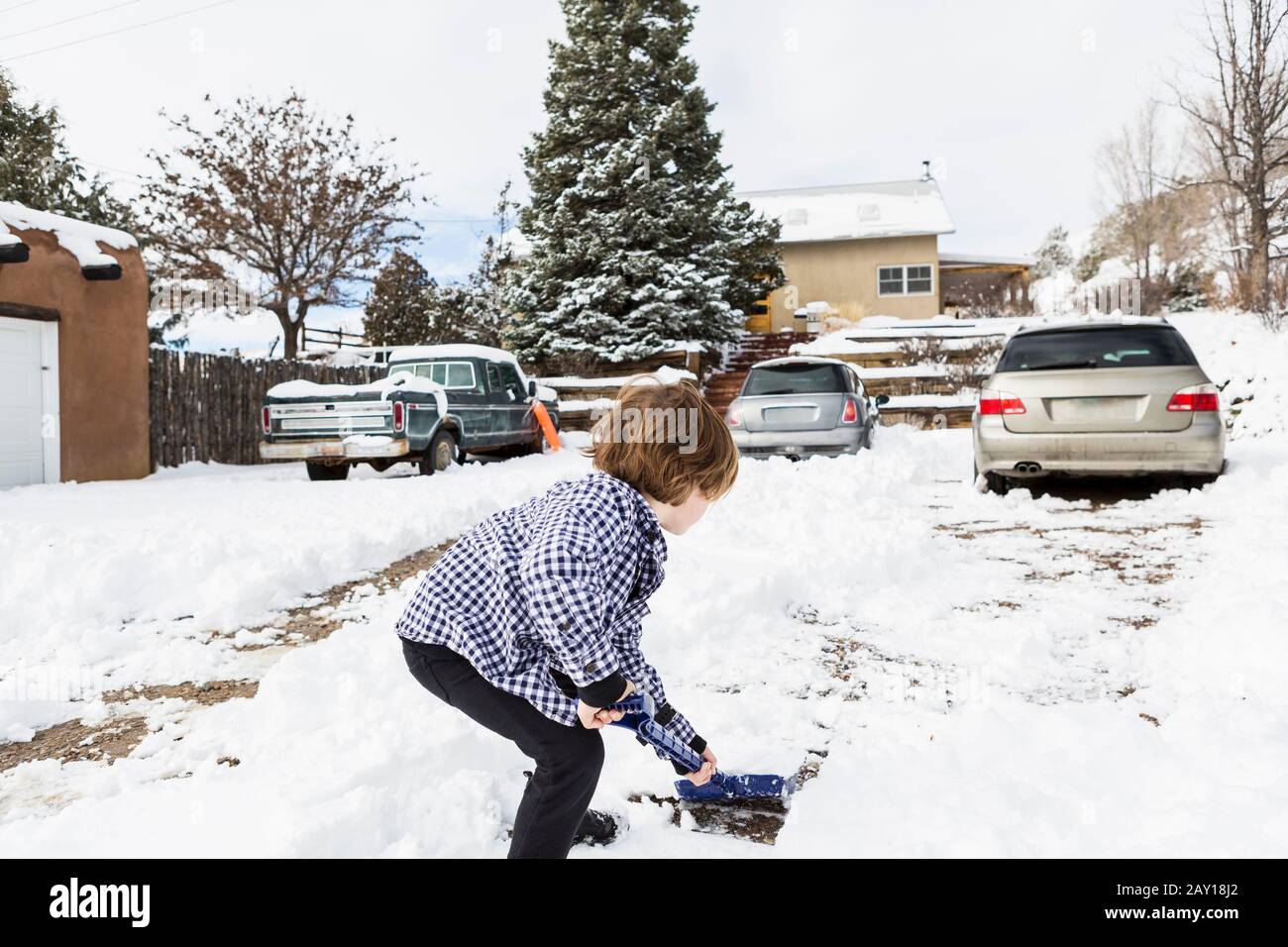 A six year old boy shoveling snow in driveway Stock Photo