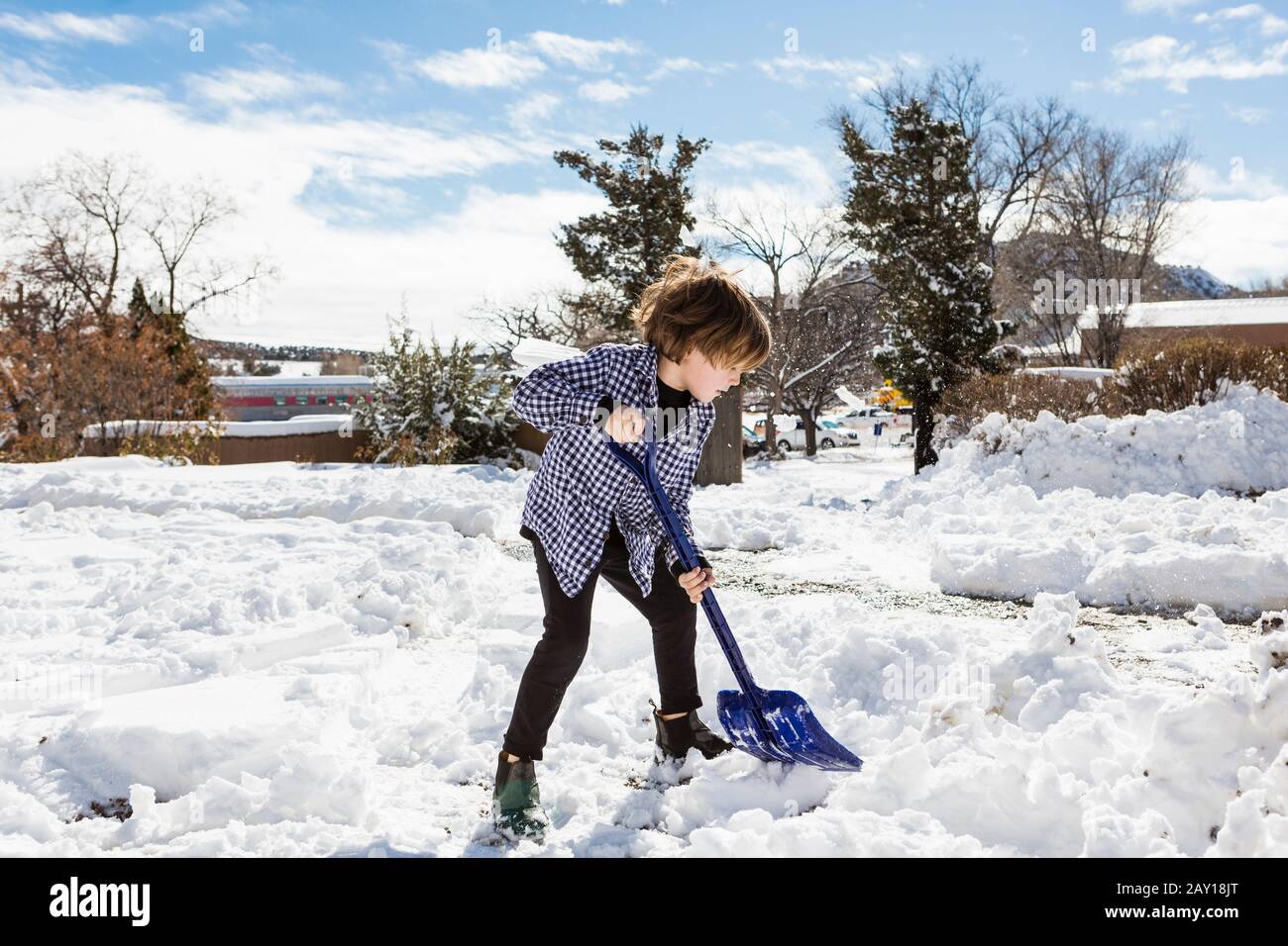 A six year old boy shoveling snow in driveway Stock Photo