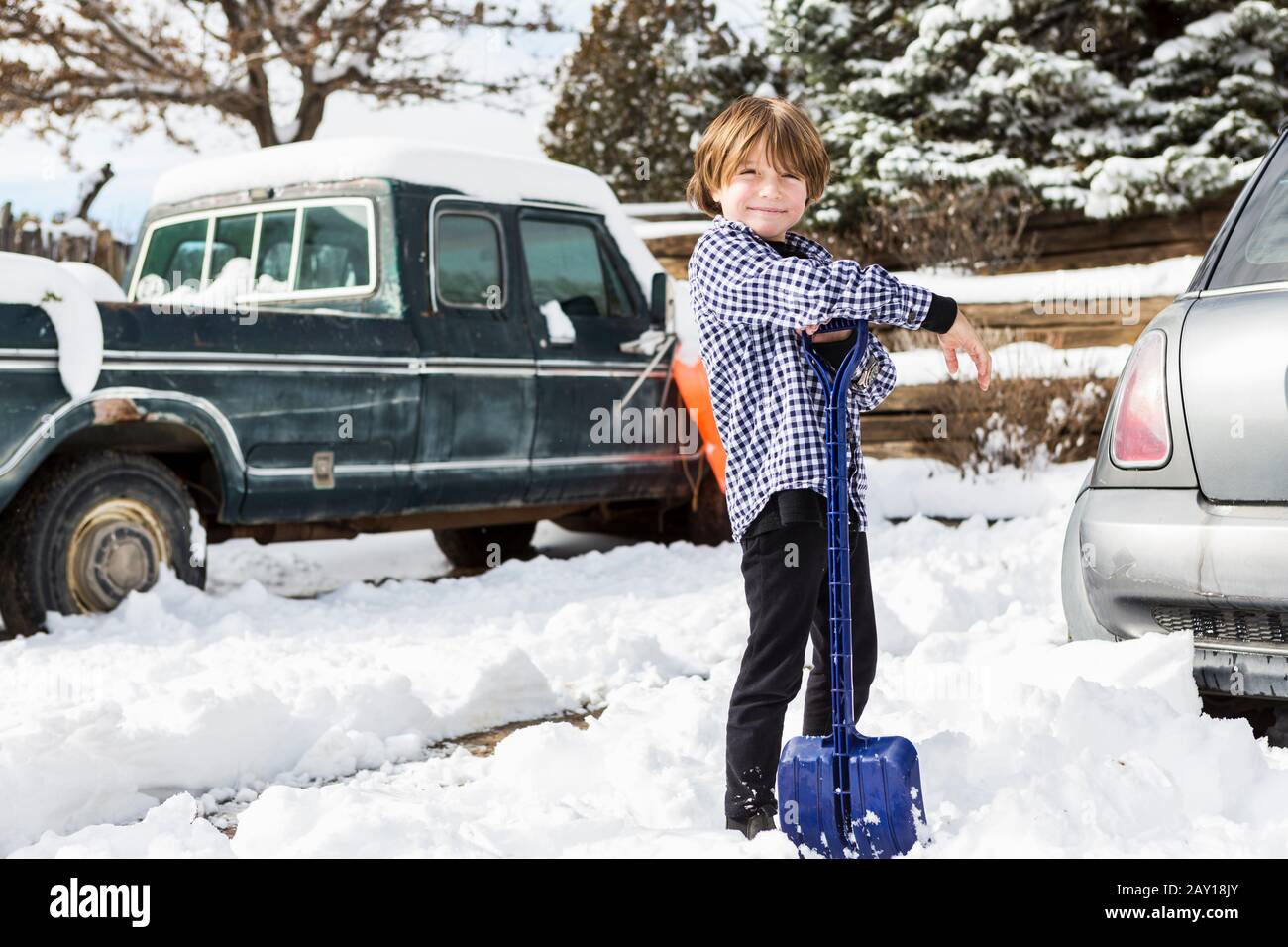A six year old boy shoveling snow in driveway Stock Photo