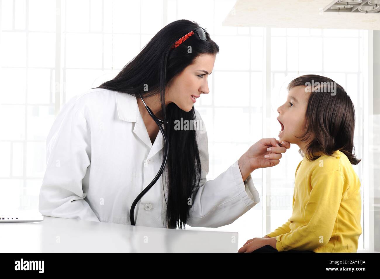 Female doctor examining child with tongue depressor Stock Photo Alamy