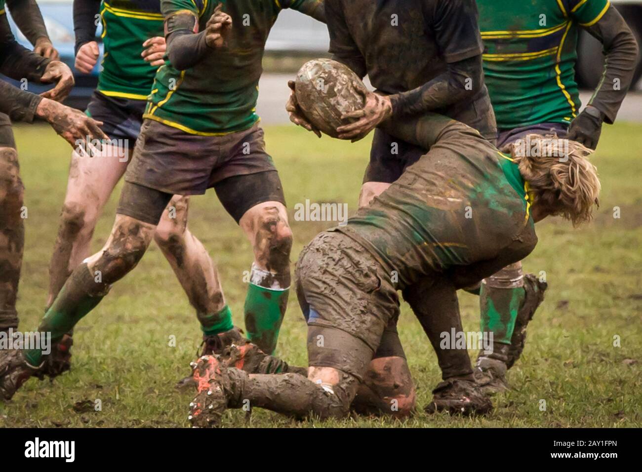 Rugby tackle taking place during an extremely muddy rugby match Stock Photo